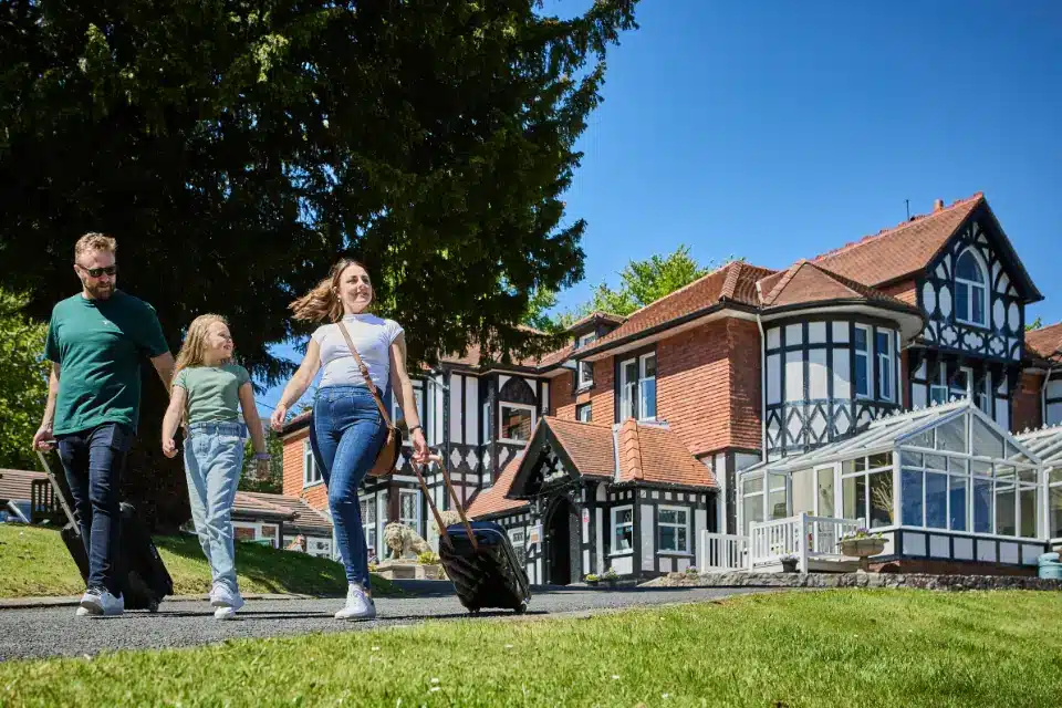 Family walking to Woodlands Hall hotel ready to check-in to their uk forest holiday
