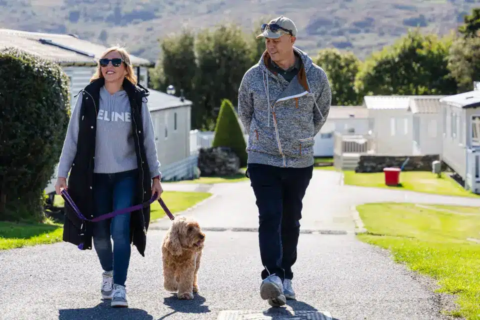 Couple walking their dog through Lyons Holiday Parks North Wales holiday park