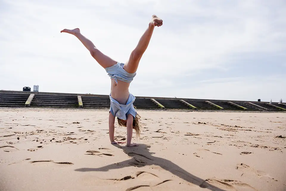 Girl doing a cartwheel on Prestatyn Central Beach